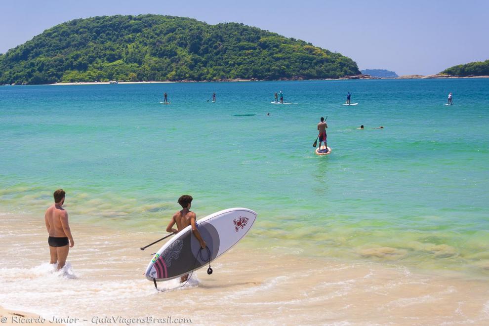 Imagem de várias pessoas praticando standup paddle na Praia de Prumirim.